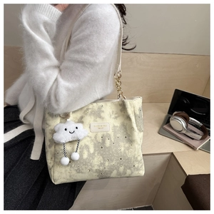 Close-up of star print tote bag with plush cloud charm and metal chain strap