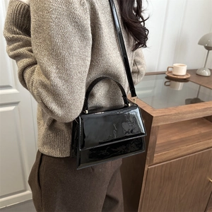 Minimalist black patent leather crossbody bag with top handle and adjustable strap
