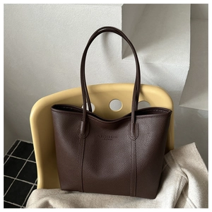 Detail of lychee textured dark brown leather tote bag with embossed fashion text logo