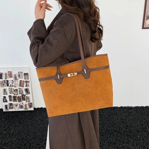 Brown faux suede tote bag with leather straps shown on a shoulder in a minimalist setting