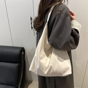 Minimalist beige oversized tote bag in soft PU leather worn by a model in a studio