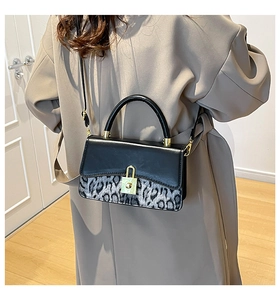 Detail view of leopard print crossbody bag with sleek black flap and gold lock closure