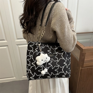 Minimalist black tote bag with white stars and plush cloud charm worn by a model
