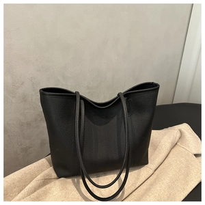 Detailed close-up of high-quality lychee grain leather texture on a black tote bag