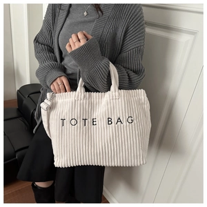 Detail of white corduroy tote bag with black embroidery on stylish textured fabric