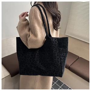 Detail view of large leopard print tote bag on shoulder over camel wool coat