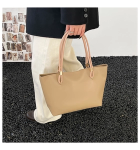 Détail du sac cabas en cuir kaki avec boucles en métal et longues anses de style minimaliste
