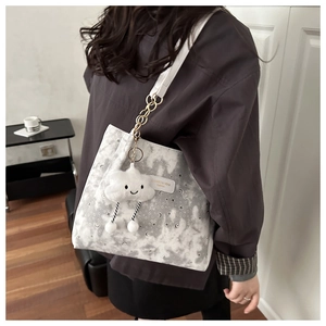 Detail of grey tote bag with star moon print and plush cloud charm on shoulder