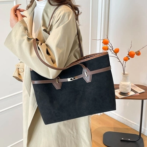 Retro black suede tote bag with brown leather straps and metal buckle shown on a model