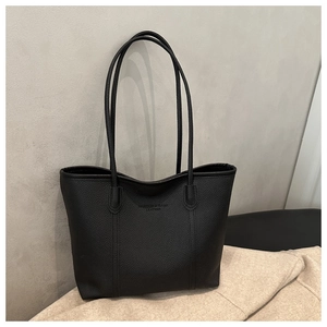 Detail of black pebbled leather tote bag with embossed lettering and shoulder straps