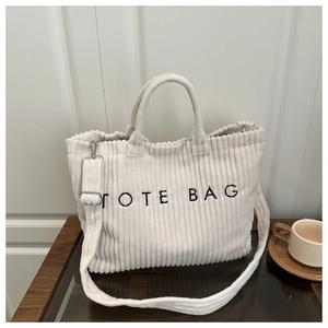 Detail of off-white corduroy tote bag featuring TOTE BAG embroidery and silver hardware