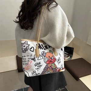 White tote bag with colorful graffiti bear prints and leather straps in a modern setting