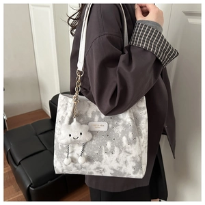 Detail of grey star and moon print tote bag with a white plush cloud charm accessory