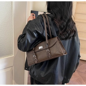 Détail du sac porté épaule rétro marron avec boucles argentées et veste en cuir noir