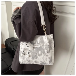 Detail of grey tote bag with celestial prints and fluffy cloud charm on model