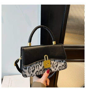 Detailed view of women's leopard print handbag with golden padlock closure and leather handle