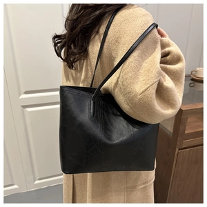 Detail of black tote bag featuring embossed textured patterns and slim double straps