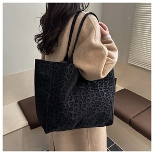 Macro shot of stylish black leopard print tote bag fabric with thin shoulder strap