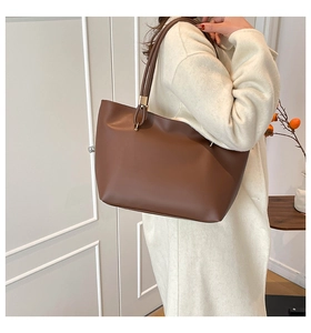 Brown leather tote bag side view with long shoulder strap and gold hardware accents