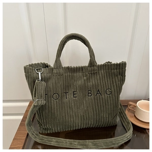 Close-up of dark green corduroy tote bag featuring TOTE BAG embroidery and adjustable strap