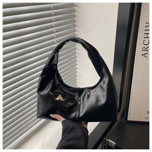 Close-up of black glossy patent leather Hobo bag with central vertical stitching detail