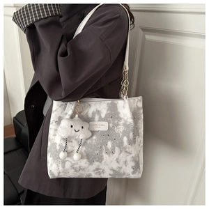 Detail of white star pattern tote bag with silver chain strap and cloud plush charm