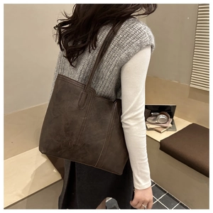 Detail view of large dark brown leather tote bag with vintage texture on female model