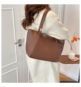 Sac cabas en cuir marron avec de fines bandoulières et des boucles dorées au style épuré