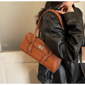 Gros plan du sac sous le bras en cuir marron avec fermoir rotatif argenté et boucles