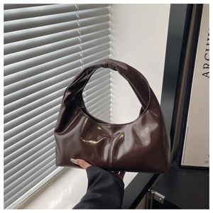 Detail of dark brown glossy tote bag featuring unique twisted pleated handle and sleek finish