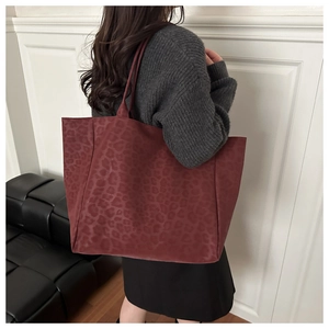Detail view of large burgundy tote bag with vintage leopard pattern worn on shoulder