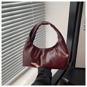 Detail of burgundy glossy faux leather hobo bag with retro pleated design and round handle