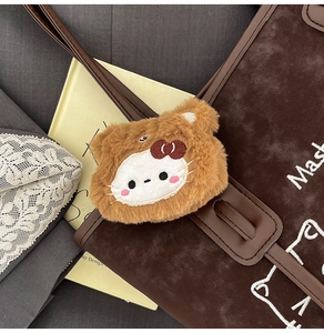 Detailed close-up of a brown plush cat charm hanging on a vintage textured tote bag