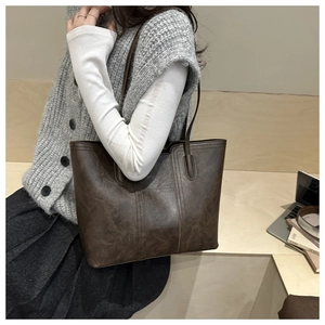 Detail of dark brown faux leather tote bag with vintage texture and vertical stitching