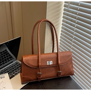 Détail d'un sac à main marron avec fermoir rotatif argenté et lanières décoratives