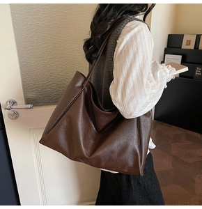 Deep brown leather tote bag detail showing large capacity and long shoulder strap