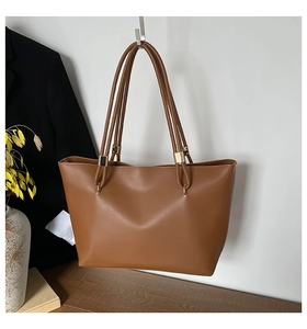 Détail du sac cabas en cuir marron mat montrant les fines anses et les boucles dorées