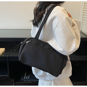 Detail of minimalist black canvas tote bag with front zipper and functional side drawstrings