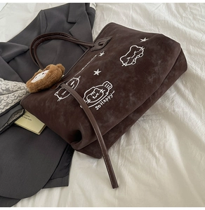 Detail of dark brown suede tote bag featuring white cat embroidery and So Happy text