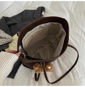 Top view of brown tote bag interior with zipper pocket and plush bear charm accent