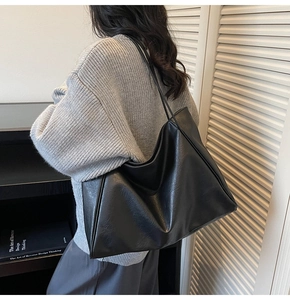 Detail of minimalist black large-capacity tote bag showing texture and shoulder fit on model