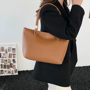 Grand sac cabas en cuir marron pour femme avec détails dorés porté à l'épaule