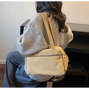 Detail view of a bright yellow minimalist canvas shoulder bag with a functional front zipper