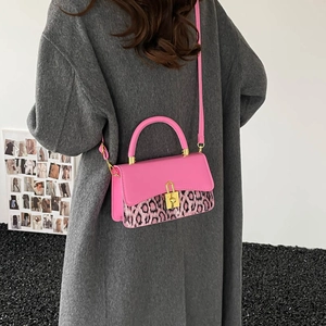 Pink leather crossbody bag with leopard print panel and gold lock worn by a model