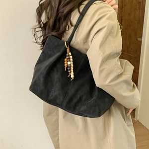 Retro black suede tote bag with decorative wooden beads on a stylish trench coat model