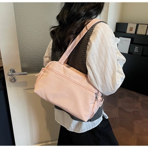 Detail of light pink nylon tote bag with double zippers and large front pocket on model