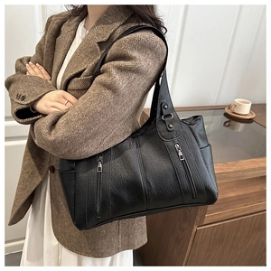 Detail of black large capacity tote bag with front zippers on wool blazer model