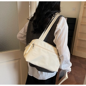 Close-up of beige minimalist tote bag showing front zipper pocket and strap detail