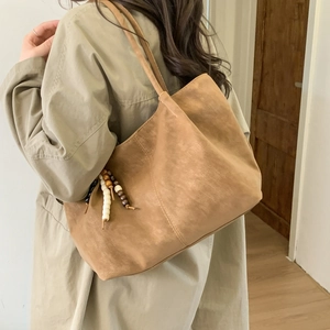 Large capacity brown suede tote bag with beaded tassel shown on model shoulder