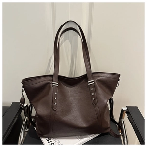 Close-up of brown tote bag with silver star rivets and lychee grain texture